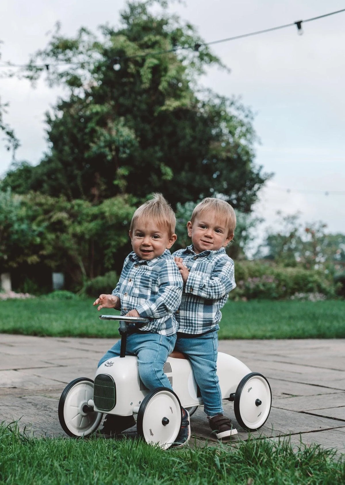 Two toddlers sitting on the Vilac ride-on car