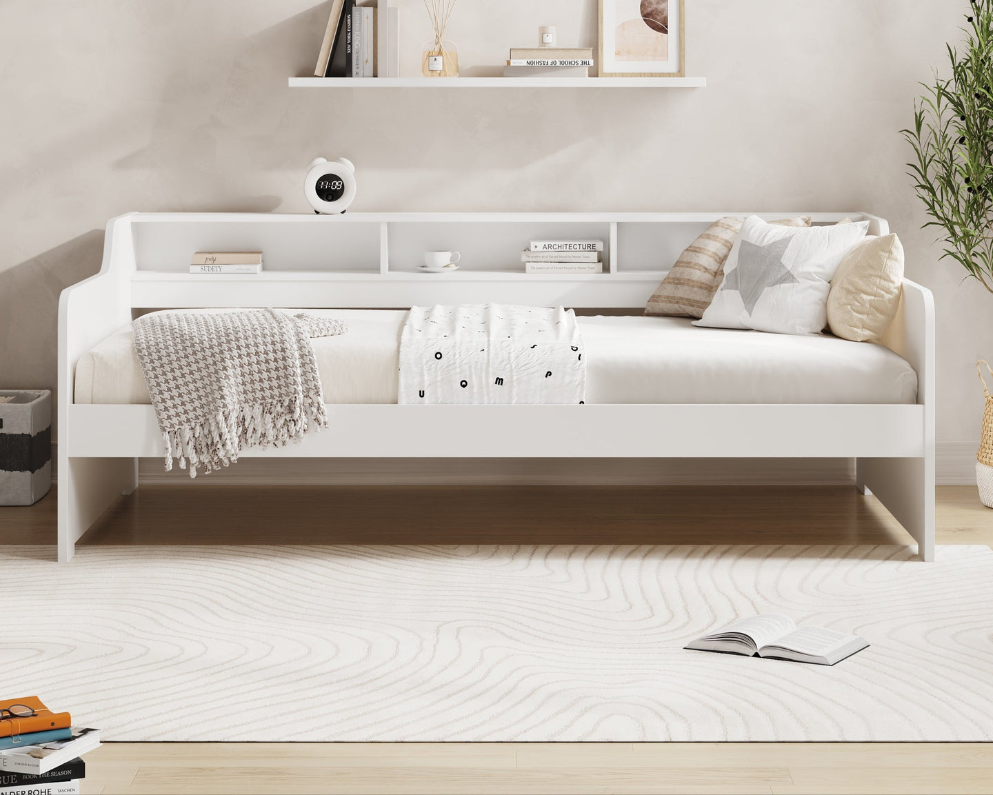 White bed with pillows and a blanket in a room with a shelf and plant, featuring 'Millie & Jones' branding.