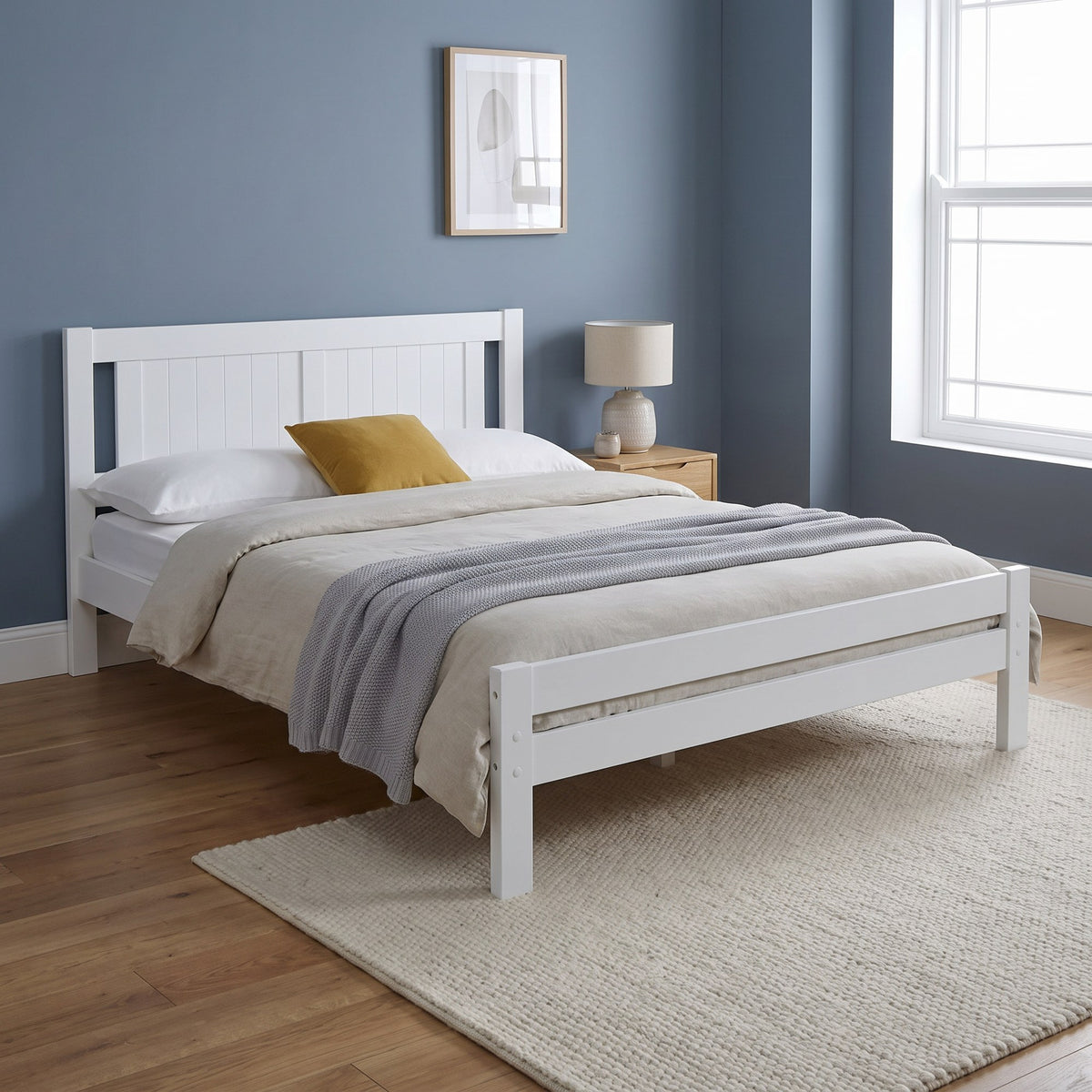 Elysian white wooden double bed with a tongue and groove headboard and low foot end, in a blue bedroom with oak floor and cream rug