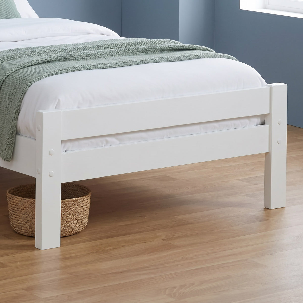 Close-up of the Elysian low foot end: two white rails between square posts with round plugs, on square legs
