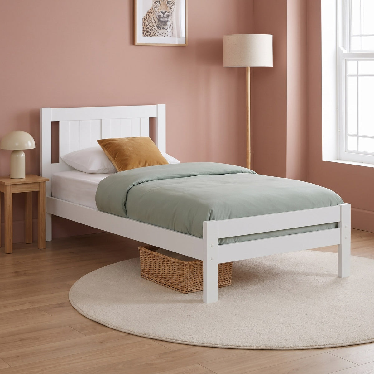Elysian white wooden single bed in a clay pink child's bedroom with sage bedding and a woven basket underneath